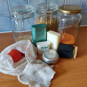 Image of grouped of items including, soap bars, jars of dry goods and reusable bags and tins.   